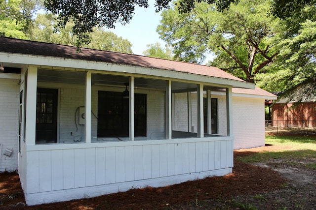 view of side of property featuring brick siding, fence, and roof with shingles