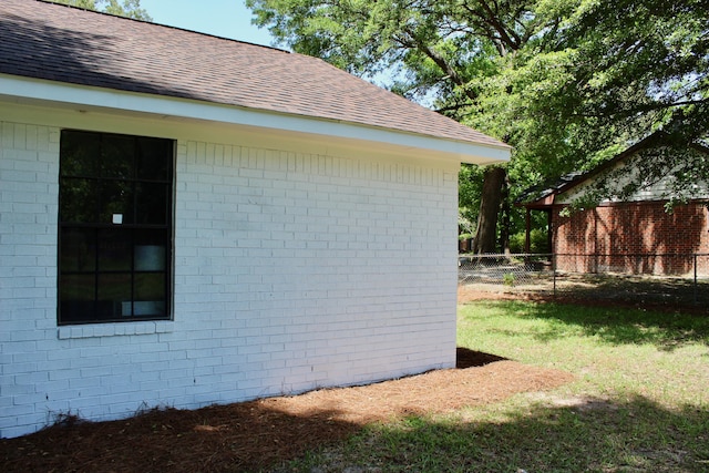 view of property exterior featuring roof with shingles and brick siding