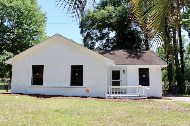view of front of home featuring roof with shingles, brick siding, and a porch