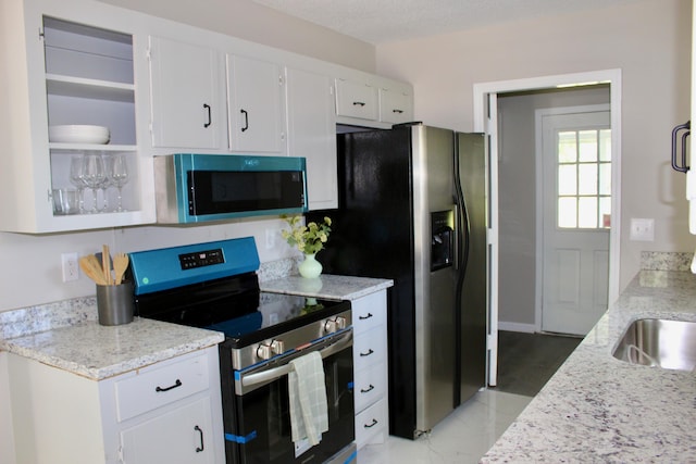 kitchen with appliances with stainless steel finishes, white cabinets, light stone countertops, and light marble finish floors
