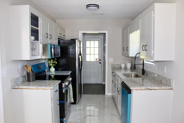 kitchen with appliances with stainless steel finishes, a sink, light marble finish flooring, white cabinetry, and a textured ceiling
