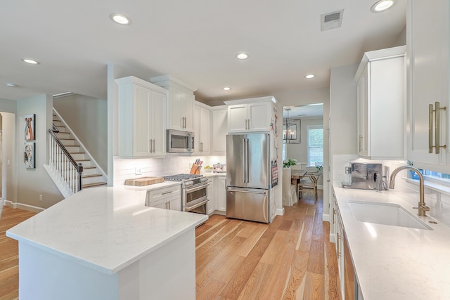 2150 Terrabrook Ln, Charleston, SC 29412 - kitchen featuring high end appliances, light wood-style floors, tasteful backsplash, white cabinetry, and a peninsula