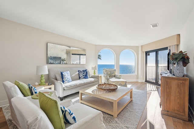 living room with light hardwood / wood-style floors and a water view