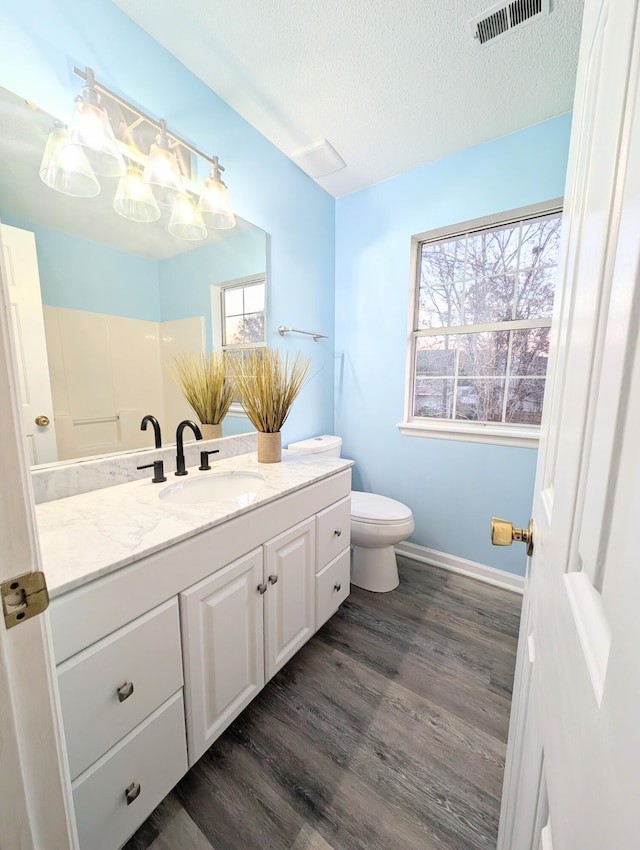 bathroom featuring vanity, hardwood / wood-style flooring, toilet, a textured ceiling, and walk in shower