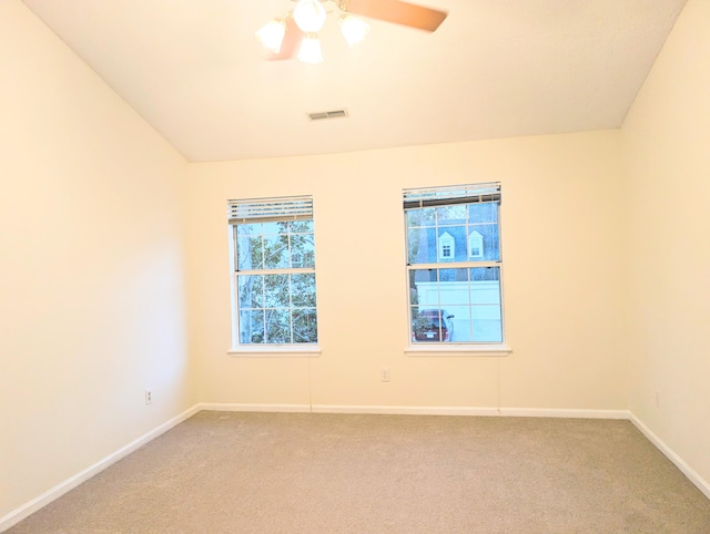 carpeted spare room featuring ceiling fan and vaulted ceiling