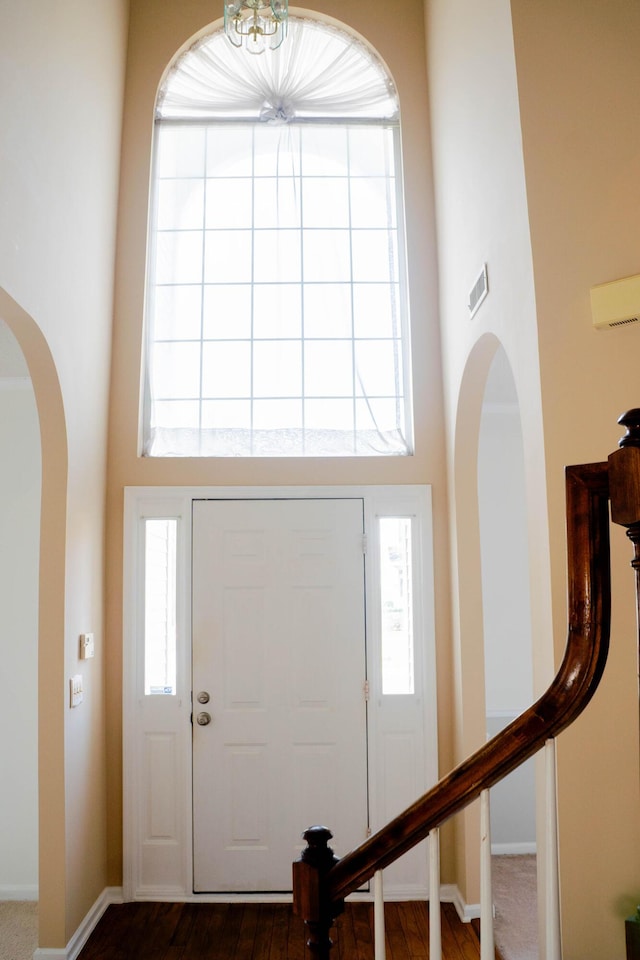 entrance foyer with a towering ceiling and dark wood-type flooring