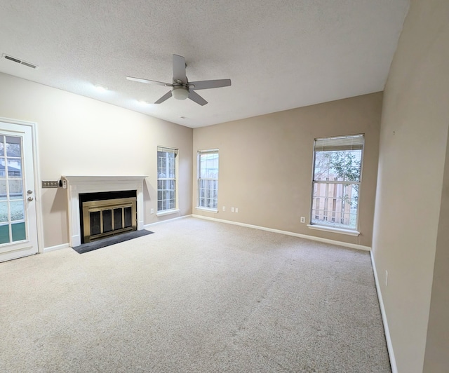 unfurnished living room featuring a textured ceiling, light colored carpet, ceiling fan, and a healthy amount of sunlight