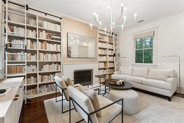 living room with hardwood / wood-style floors, crown molding, a notable chandelier, and a premium fireplace