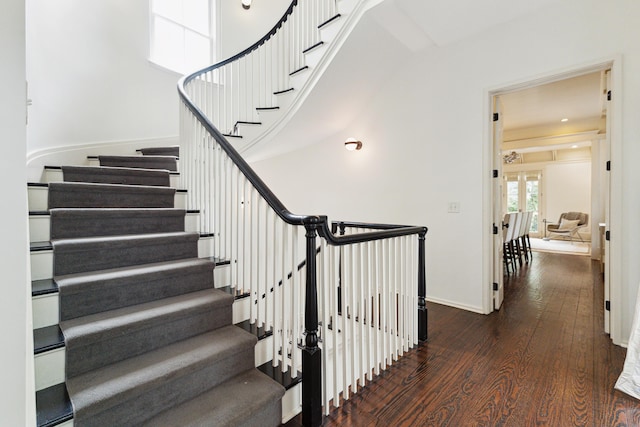 stairs with wood-type flooring, a towering ceiling, and french doors