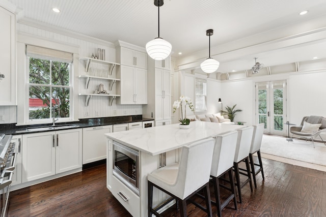 kitchen with dark stone countertops, hanging light fixtures, white cabinetry, and stainless steel appliances