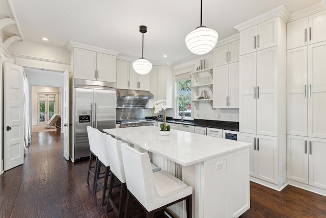 kitchen featuring pendant lighting, built in refrigerator, a center island, and white cabinets