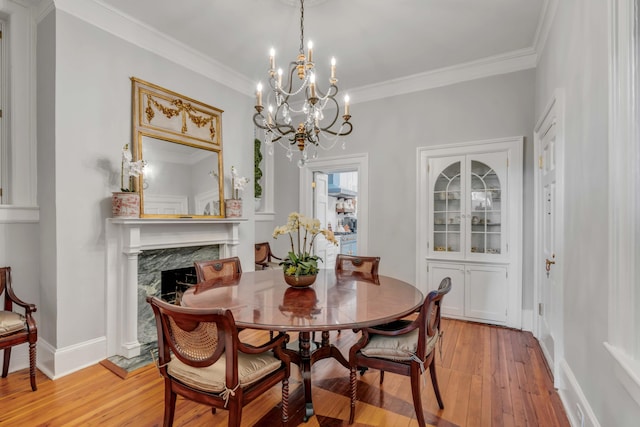 dining area with crown molding, a high end fireplace, and light hardwood / wood-style floors