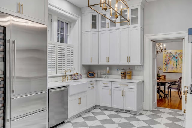 kitchen with an inviting chandelier, appliances with stainless steel finishes, sink, and white cabinets