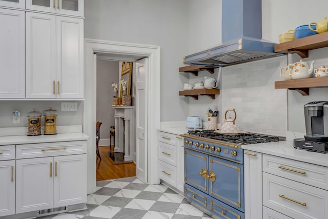 kitchen featuring range, white cabinetry, island range hood, light stone countertops, and decorative backsplash