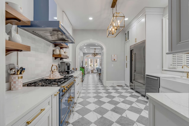 kitchen featuring decorative light fixtures, white cabinetry, island exhaust hood, high end appliances, and light stone counters