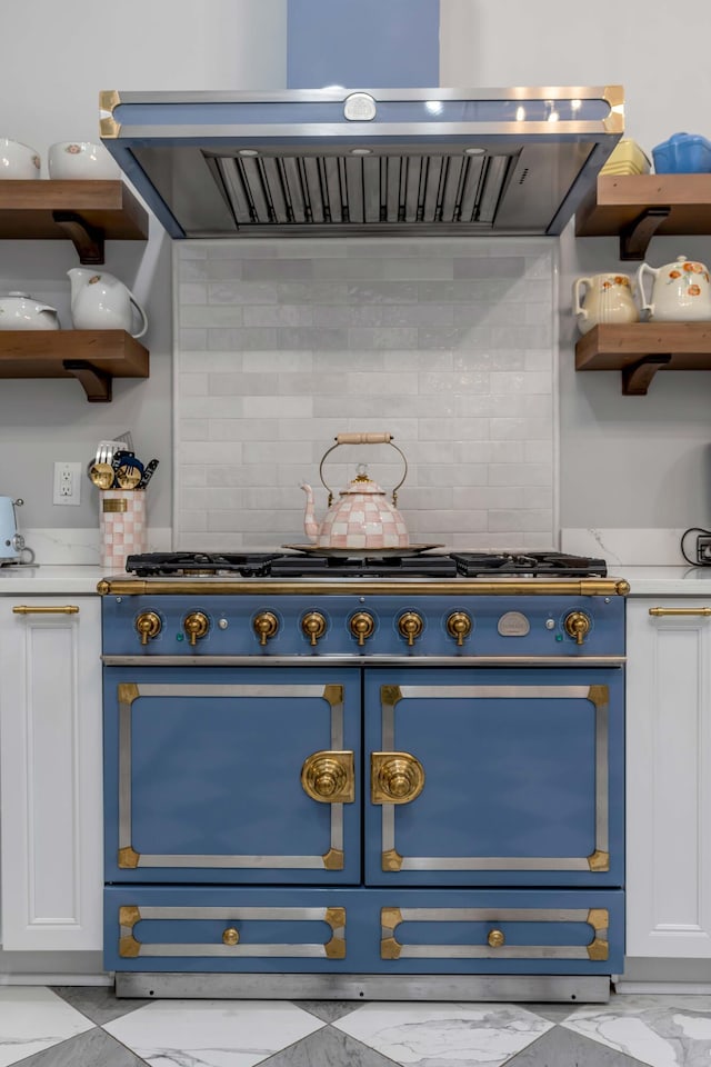 kitchen with white cabinetry, wall chimney range hood, decorative backsplash, and range with two ovens