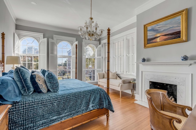 bedroom with crown molding, a premium fireplace, a chandelier, and light wood-type flooring