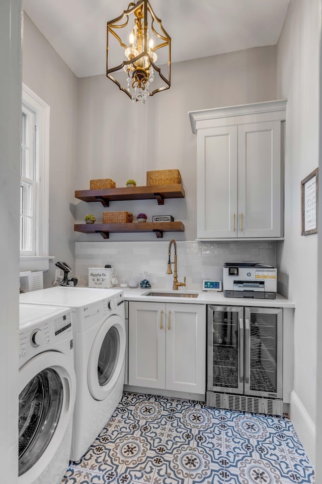 washroom featuring sink, wine cooler, cabinets, light tile patterned floors, and washing machine and clothes dryer