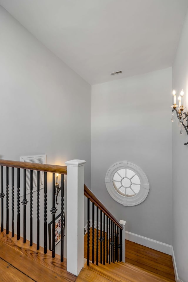 stairway with wood-type flooring and a chandelier