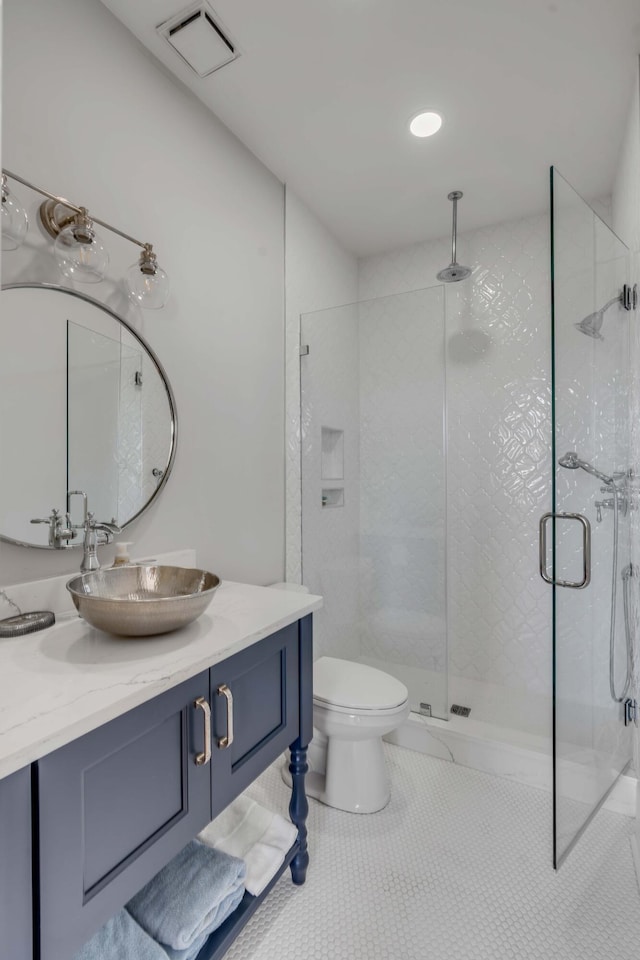 bathroom with a shower with door, vanity, tile patterned floors, and toilet