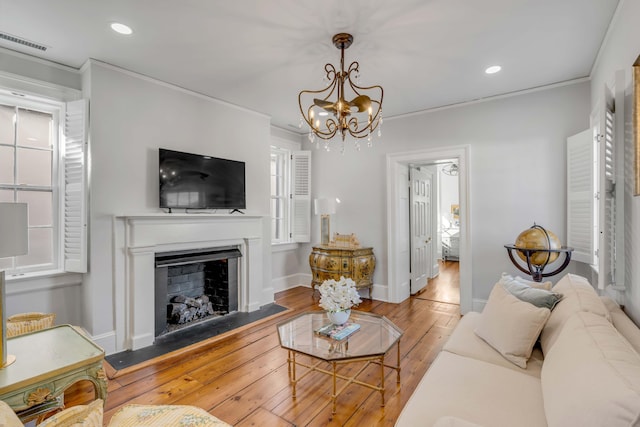 living room featuring crown molding, light hardwood / wood-style floors, and a notable chandelier