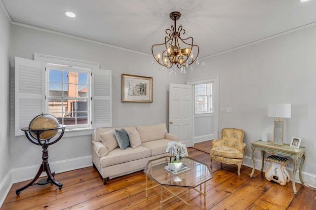 living room featuring ornamental molding, a healthy amount of sunlight, hardwood / wood-style floors, and a notable chandelier