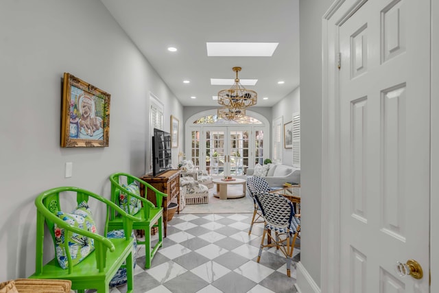 hall with french doors, a skylight, and an inviting chandelier