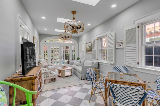 living room featuring an inviting chandelier, a skylight, and french doors