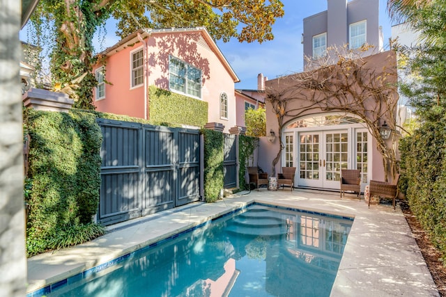 back of property with a fenced in pool, a patio area, and french doors