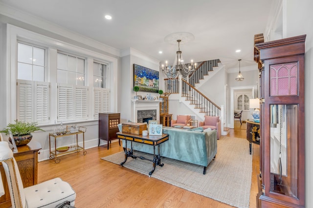 living room with crown molding, wood-type flooring, a fireplace, and a chandelier