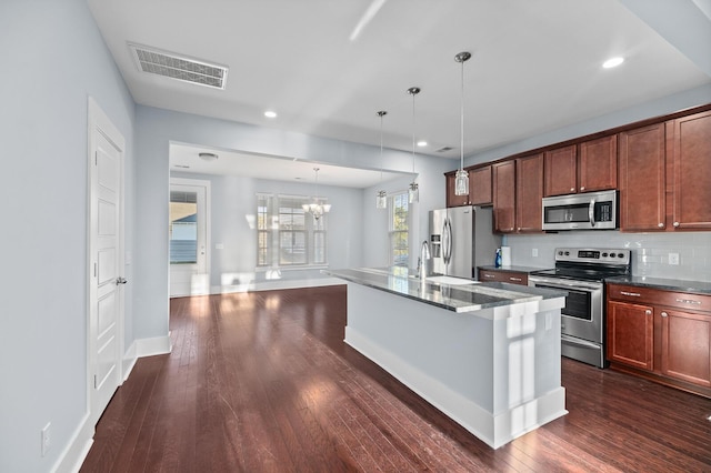 kitchen with stainless steel appliances, a kitchen island with sink, pendant lighting, a chandelier, and dark hardwood / wood-style floors