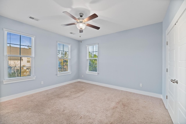 carpeted spare room featuring ceiling fan and a healthy amount of sunlight