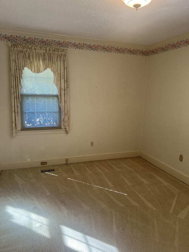 empty room with ornamental molding, visible vents, light carpet, and baseboards