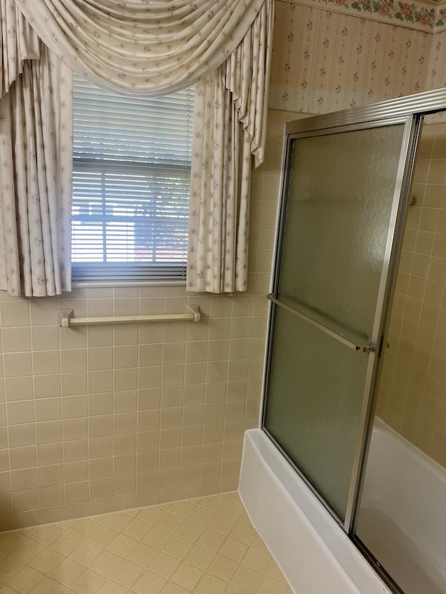 full bathroom with tile patterned floors, shower / bath combination with glass door, tile walls, and wallpapered walls