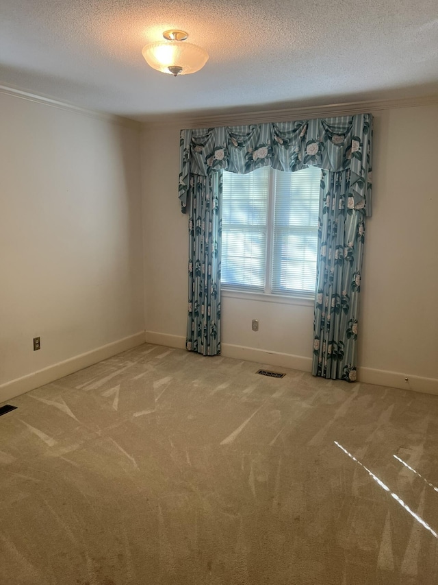 unfurnished room featuring carpet, visible vents, a textured ceiling, and baseboards