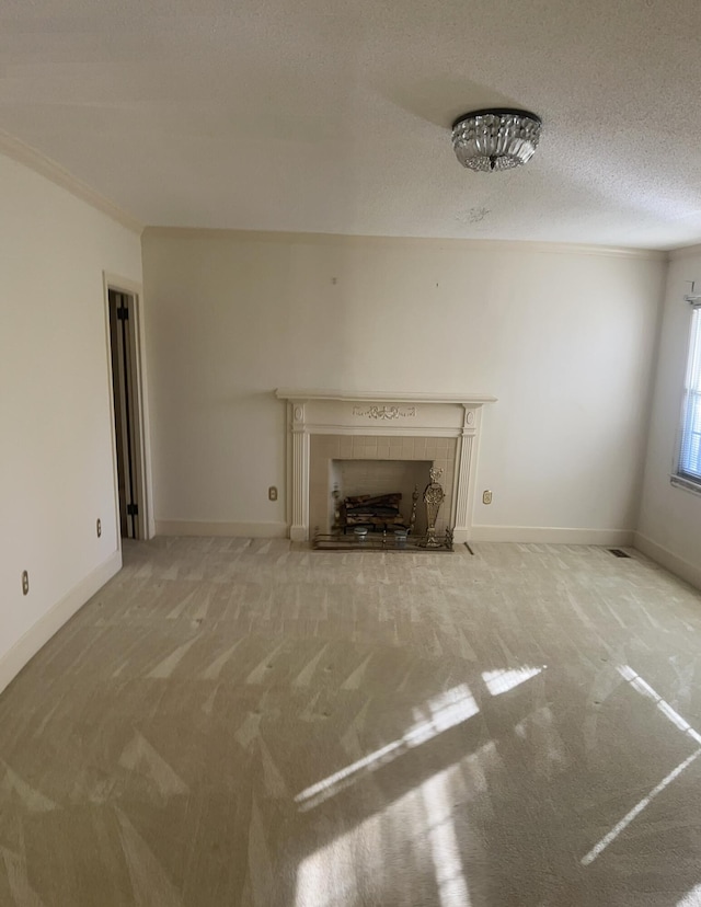 unfurnished living room featuring carpet floors, crown molding, a textured ceiling, a tile fireplace, and baseboards