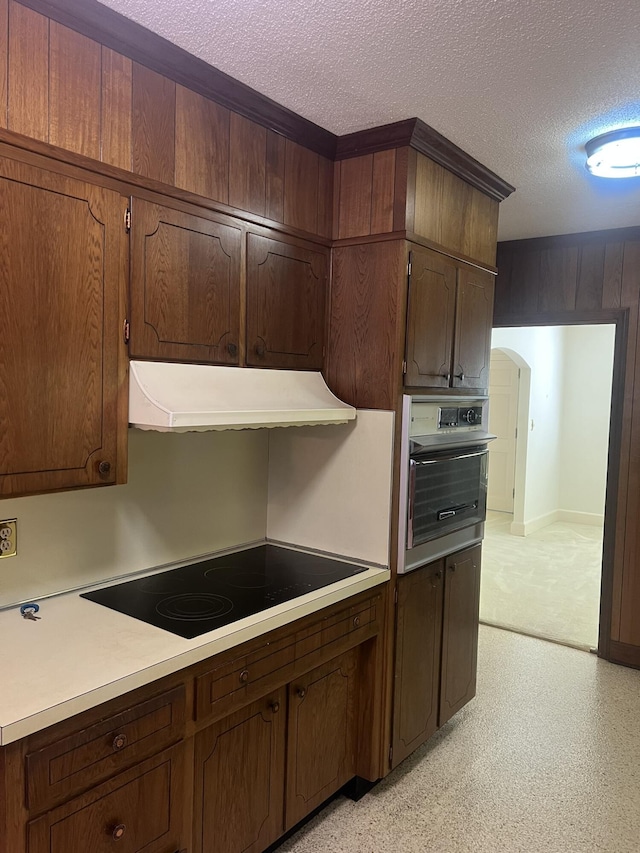 kitchen featuring black electric stovetop, light countertops, wall oven, a textured ceiling, and under cabinet range hood