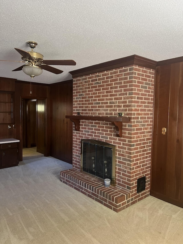 unfurnished living room featuring a textured ceiling, wood walls, a brick fireplace, and carpet flooring