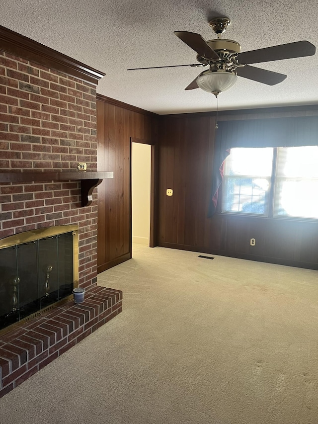 unfurnished living room featuring light carpet, a textured ceiling, a brick fireplace, and crown molding