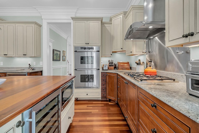 kitchen with wall chimney range hood, cream cabinetry, wine cooler, light wood-type flooring, and appliances with stainless steel finishes