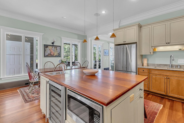 kitchen with light hardwood / wood-style floors, stainless steel appliances, a center island, sink, and pendant lighting