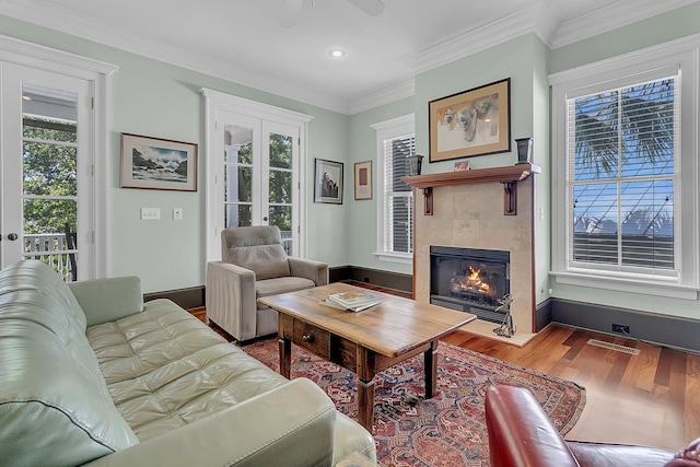 living room featuring a fireplace, ceiling fan, ornamental molding, and hardwood / wood-style floors