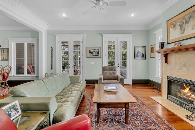 living room with crown molding, french doors, a fireplace, and hardwood / wood-style flooring