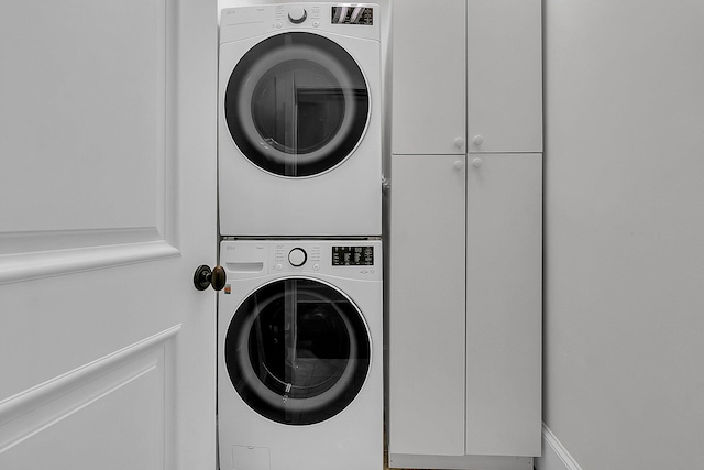 laundry room with stacked washer and dryer and cabinets