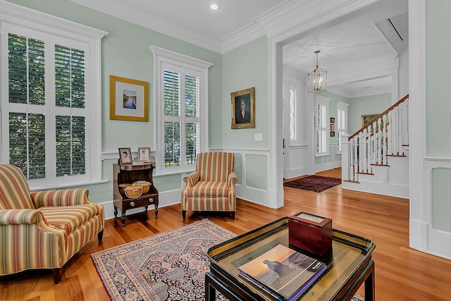 living room featuring a notable chandelier, hardwood / wood-style flooring, and ornamental molding