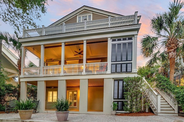 back house at dusk featuring a balcony, ceiling fan, and french doors