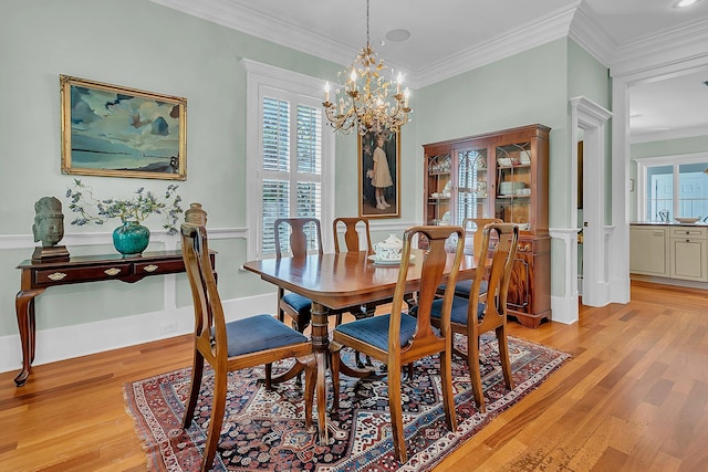 dining area with light hardwood / wood-style floors, sink, ornamental molding, and a notable chandelier