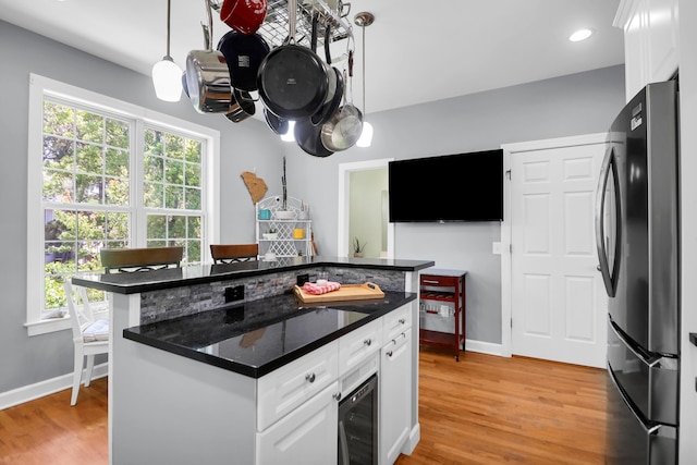 kitchen with beverage cooler, freestanding refrigerator, light wood-style floors, and plenty of natural light