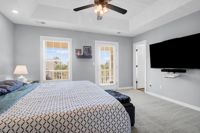 carpeted bedroom with access to outside, a ceiling fan, baseboards, a tray ceiling, and visible vents