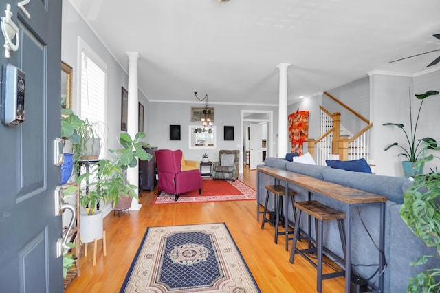 foyer entrance with crown molding, stairway, decorative columns, and wood finished floors